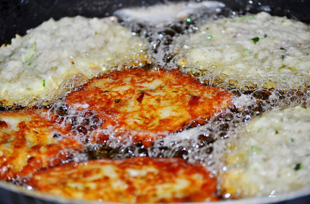 Картопляні драники під час смаження у великій кількості олії.