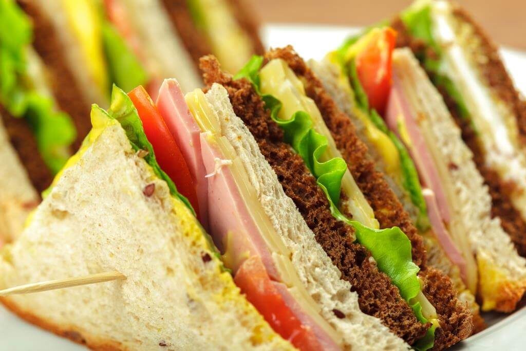 Трикутні сендвічі з шинкою, сиром, салатом і помідором крупним планом