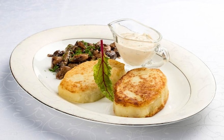 Картопляні зрази з грибами та соусом на білому тарілці