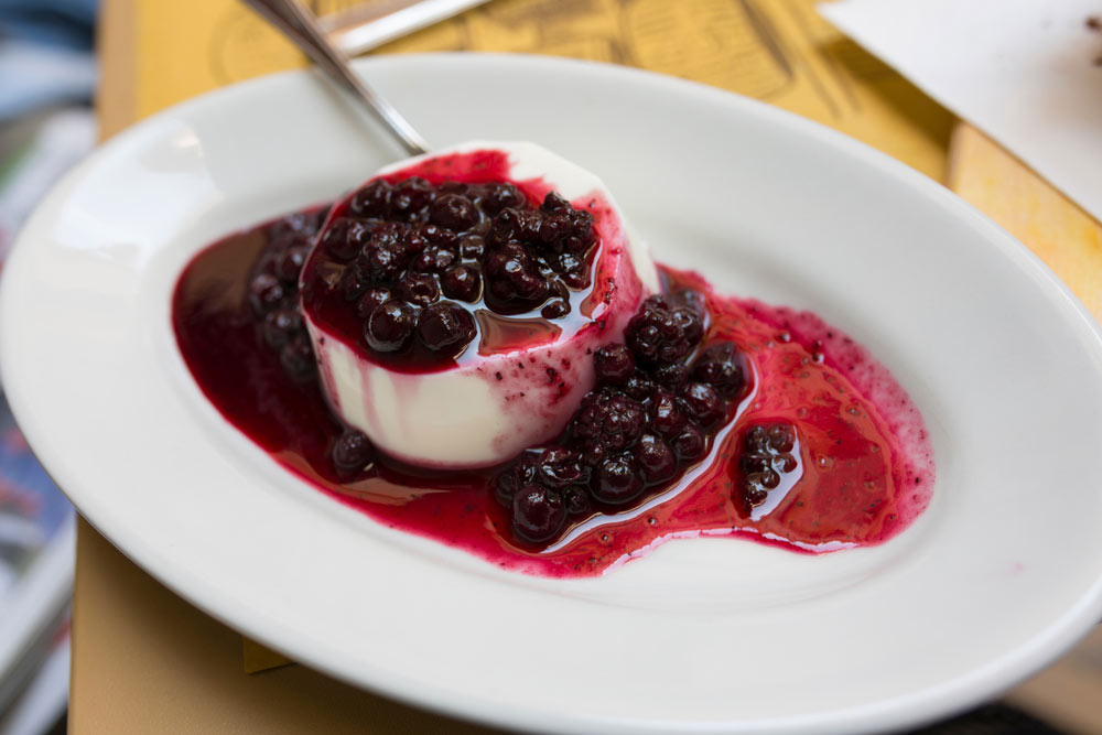 Панна котта з чорничним соусом на овальній тарілці