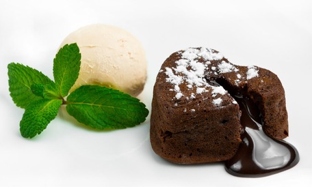 Шоколадний фондан з ванільним морозивом і м’ятою на білому тлі.