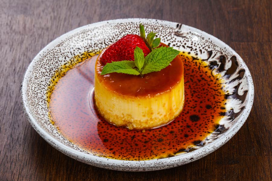 Крем-карамель із полуницею та м'ятою на плямистій керамічній тарілці