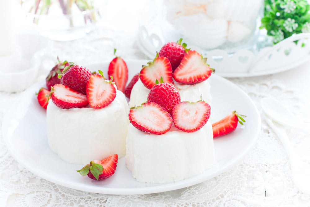 Білий десерт із полуницею, поданий на тарілці на мереживній скатертині