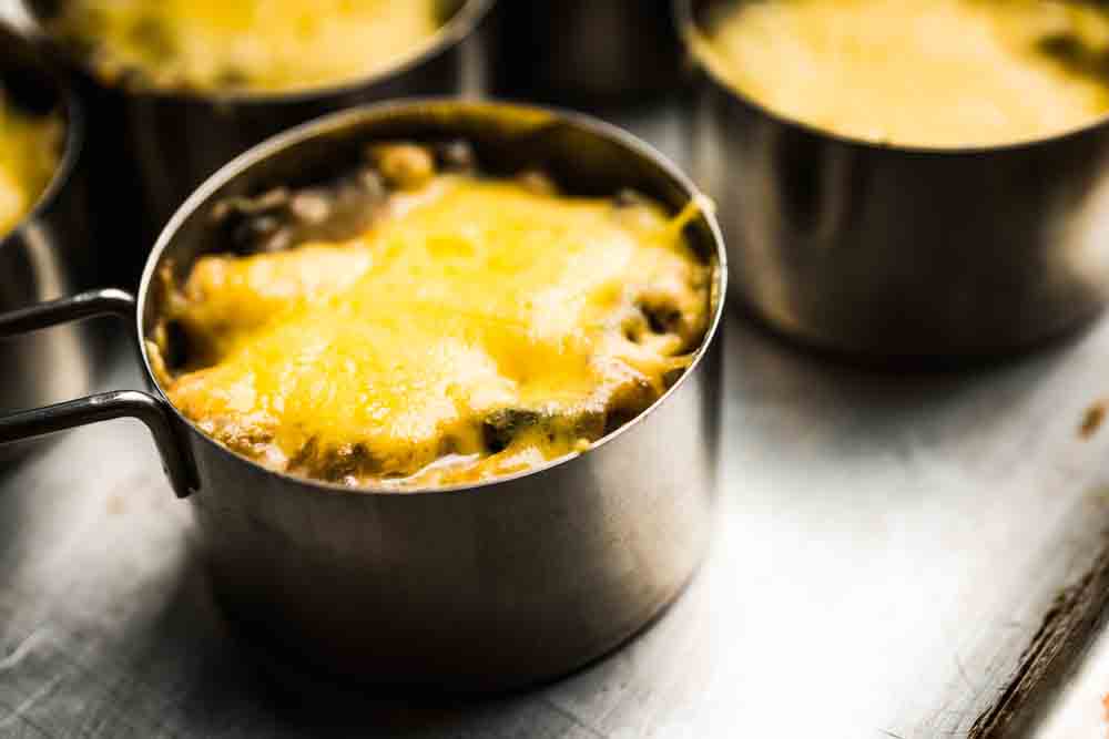 Порційний жульєн з грибами та розплавленим сиром у металевій формочці