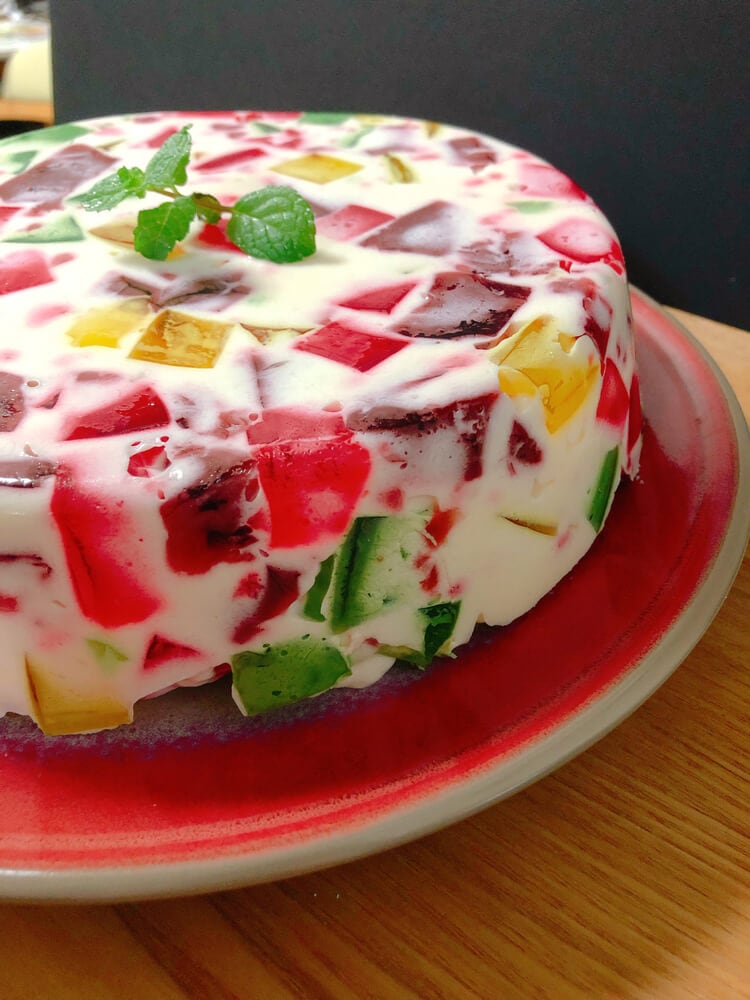 Торт із різнокольоровим желе у сметанному кремі, прикрашений м’ятою.