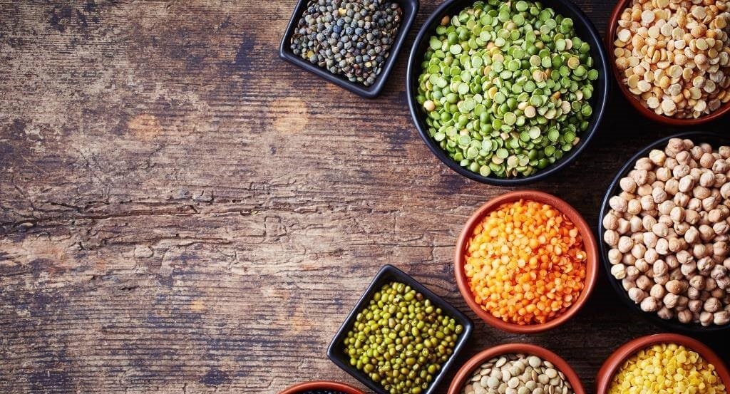 Різновиди бобових у мисках: зелена, жовта, червона сочевиця, нут і маш