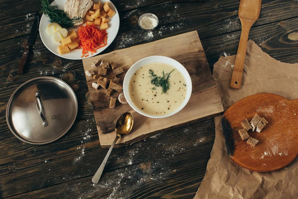 Крем-суп із зеленню у білому посуді з сухариками на дерев'яній підставці