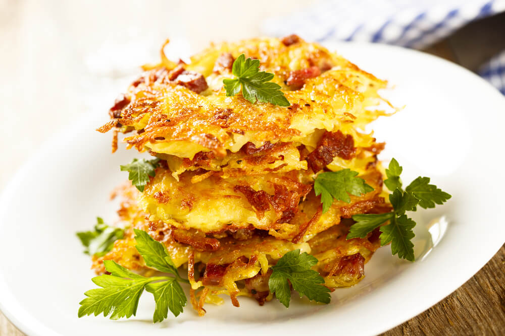 Хрусткі картопляні драники з беконом, прикрашені гілочками петрушки.