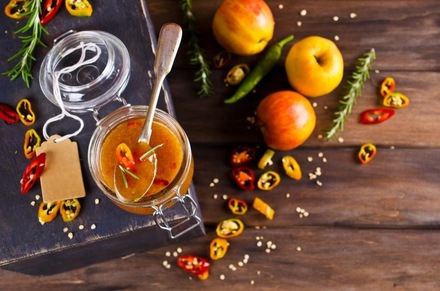 Баночка яблучного соусу з перцем чилі, яблуками та прянощами на дерев'яній поверхні