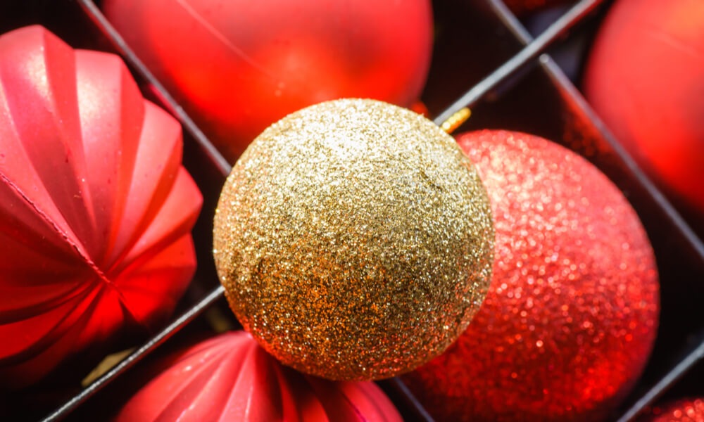 Близький план блискучих новорічних куль — золотої та червоних у коробці для прикрас.
