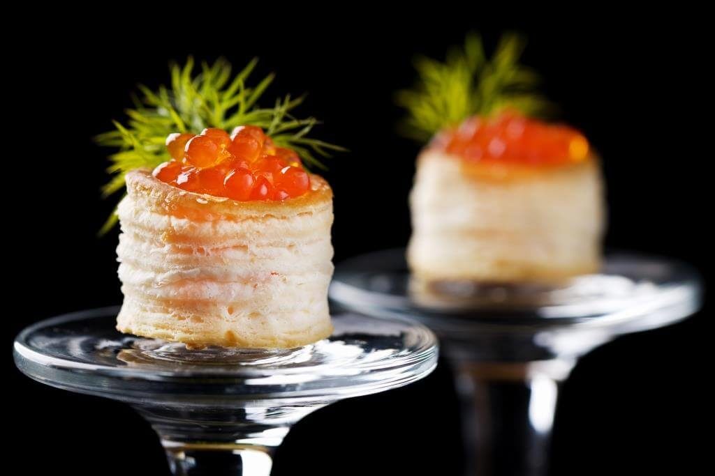 Порційна закуска з листкового тіста з червоною ікрою та кропом на прозорих келихах.