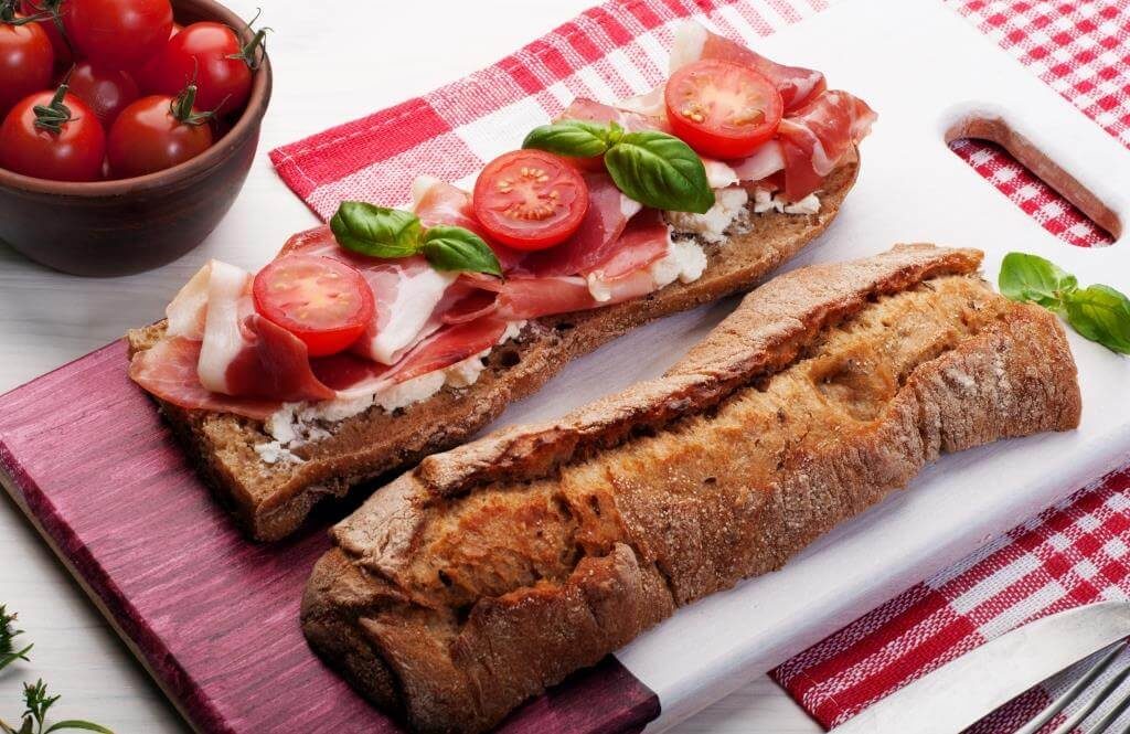 Брускетти з прошутто, сиром і помідорами чері на дерев’яній дошці