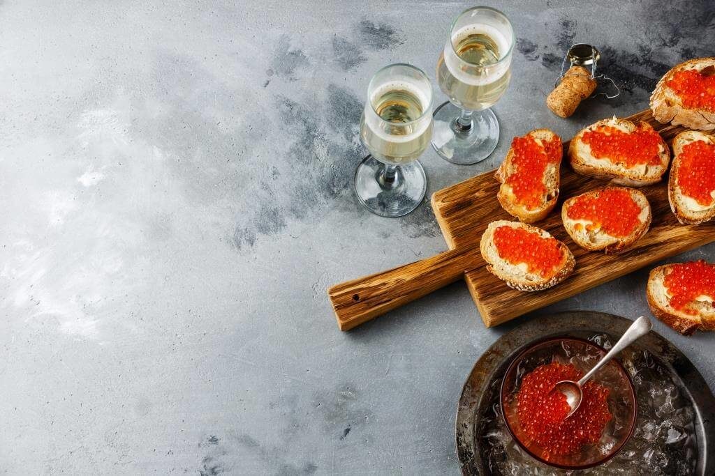 Келихи шампанського та бутерброди з ікрою на святковому столі з льодом.