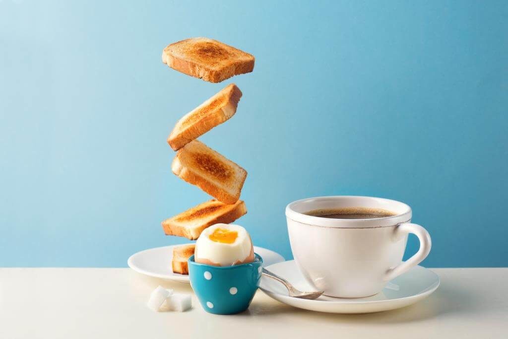 Чашка кави з підсмаженими тостами та яйцем некруто на блакитному фоні
