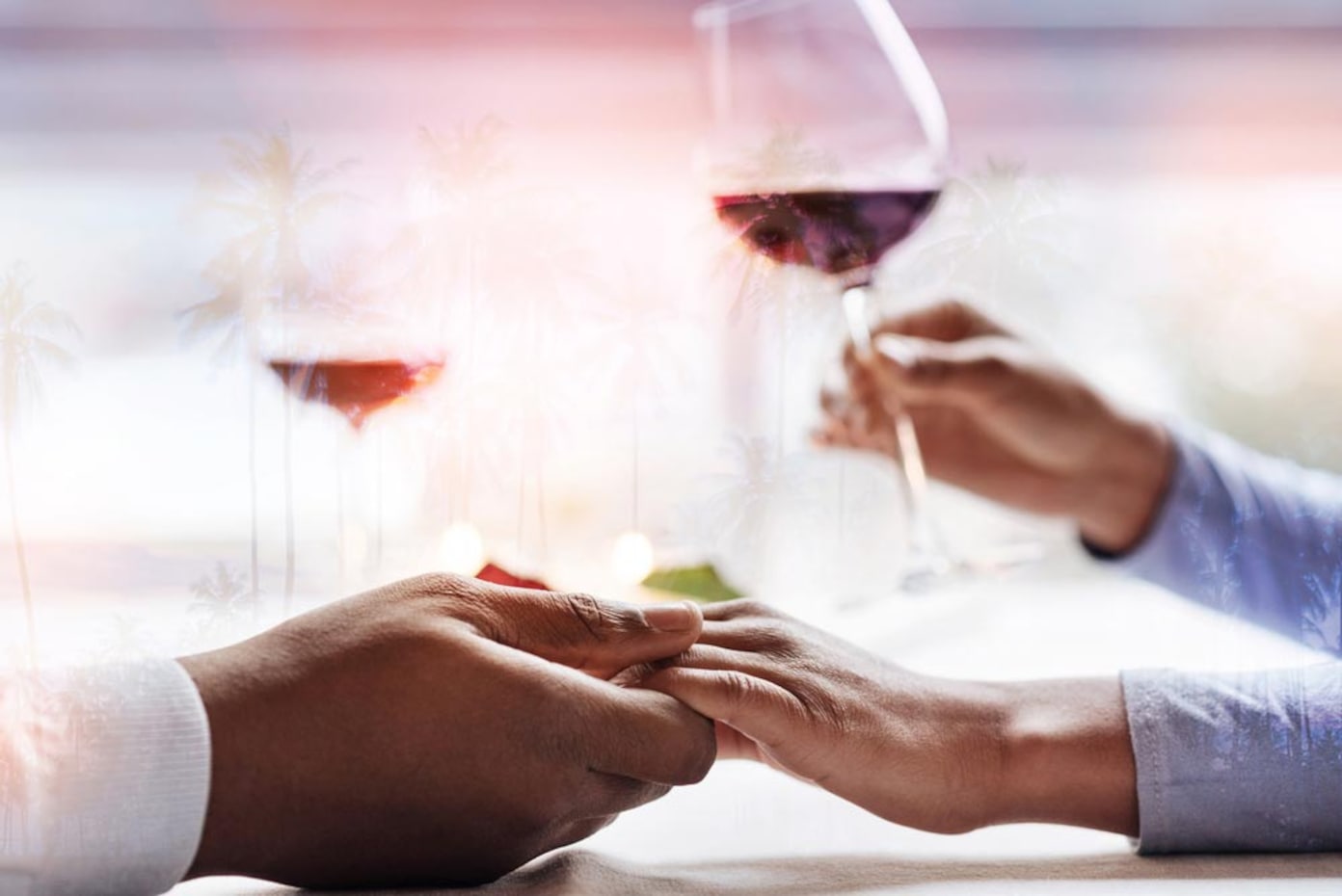 Романтична вечеря: закохана пара тримається за руки і п’є червоне вино