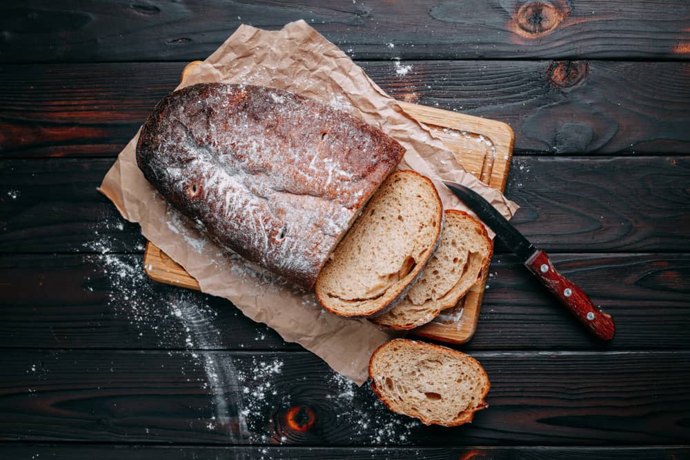 Нарізаний домашній хліб на дерев’яній дошці з ножем